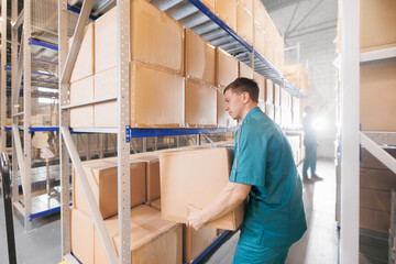 Warehouse worker in blue uniform holding package on shoulder for delivery to customer. Storage of medical products in med industry factory