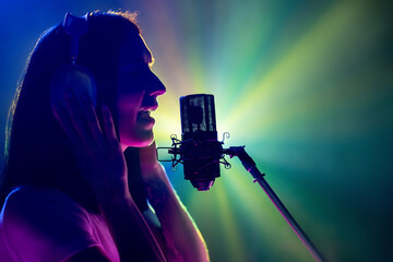 Singer's profile portrait performing new song against dynamic backdrop of red and purple concert lighting. Concept of art, work and hobby, music festivals, self expression, concert. Ad
