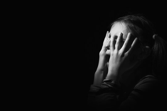 Conceptual image: lost childhood, emotional pain, and children's pain, depression and domestic violence. The girl is crying. Copy space for text or design. Black and white image.