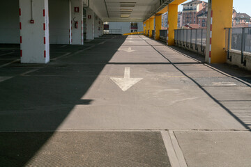 multi-storey public car park, directional arrows on the asphalt towards a ramp for the road...