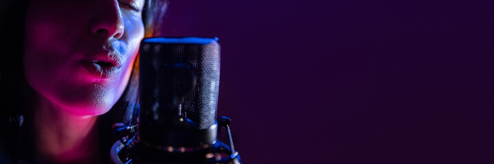 Banner. Close up of female vocalist singing passionately near studio microphone with purple flare lighting. Negative space to insert text. Concept of art, work and hobby, music festivals, concert. Ad