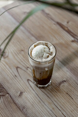 Iced coffee with whipped cream in a glass on a wooden table