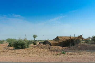 A remote desert village inside the desert. Distant horizon, Hot summer with cloudless clear blue sky background, Thar desert, Rajasthan, India.