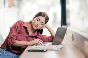 A woman is sleeping on a table with a laptop in front of her
