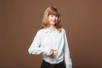 Portrait of Happy Middle-Aged Woman with Blonde Hair pointing fingers down, showing advertisement, recommending click on link, looking at camera, standing against beige background