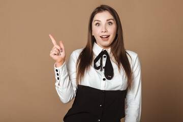 Positive and Smiling Young Woman Pointing Upwards, Signaling a Perfect Space for Your Advertisement. Cheerful Model Promoting Your Brand with Enthusiasm