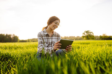Smart farm. Woman Farmer with tablet in green field. Modern digital technologies. Agronomist at the...