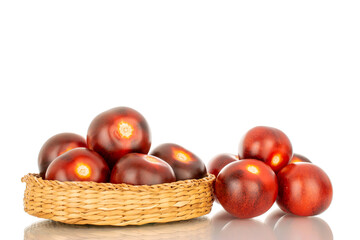 Several ripe black cherry tomatoes in a straw plate, macro, isolated on white background.