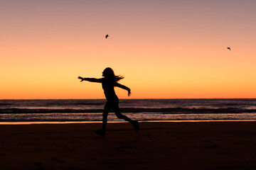 woman silhouette jumping in the beach before sunrise