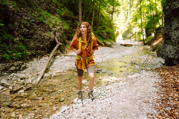 Hiking in nature. Young woman with a yellow backpack  walks along a hiking trail against the backdrop of mountain scenery. Adventure, travel, tourism.