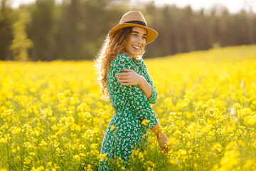 Beautiful woman walking in the field at sunny summer day. Nature, vacation, relax and lifestyle. View scenic landscape yellow flower blooming.