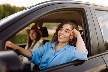 Beautiful female friends in the car enjoy a car trip together. Lifestyle, travel, tourism, nature,...