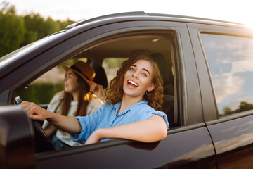 Beautiful female friends in the car enjoy a car trip together. Lifestyle, travel, tourism, nature, active life.