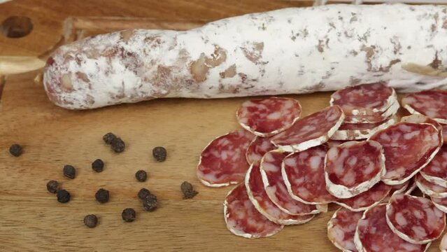saucisson sec tranch&eacute;, en gros plan, sur une planche &agrave; d&eacute;couper	