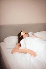 Obraz na płótnie Canvas young woman in beige silk sleep mask sleep in bed in hotel. Improving sleep quality