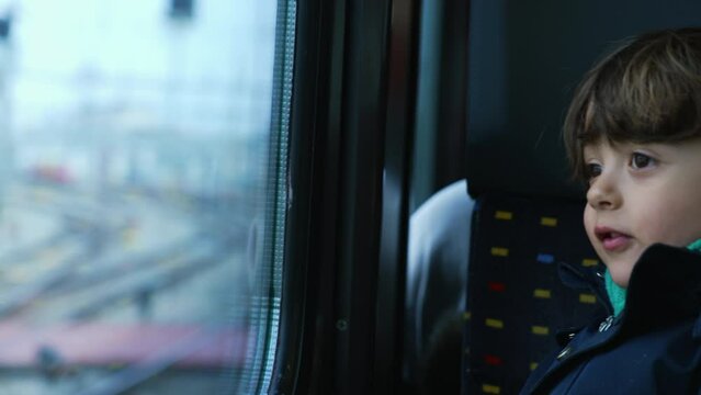 Small boy passenger staring at landscape passing by from trian window. Kid wearing scarf and jacket during autumn fall season travel