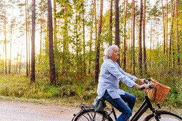 Mature retired woman cyclist riding a retro bicycle taking a rest in forest or park.