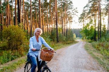 Active senior woman ridding bike in autumn nature. Retired female relaxing enjoy admire summer evening at forest.