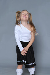 Youthful joy meets fashion flair in a girl's beaming pose, complete with whimsical pigtails and a contemporary skirt.