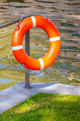 red lifebuoy on the shore of a pond