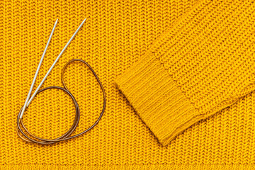 knitting needles and wool threads on a knitted background.