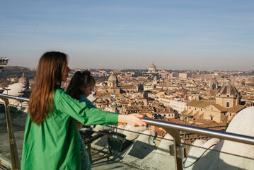 Fototapeta na wymiar young happy mom and daughter on the rooftop of the city in rome.