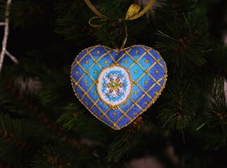 A blue cross stitch Christmas Timeless Elegance ornament on a Christmas tree. This blue and gold Christmas ornament with snowflake embroidered and made by myself.