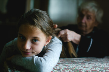 Grandma braiding a little girl's hair. - 776202531