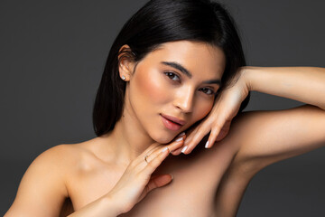 Portrait of beauty model with natural nude make up and touching her face.