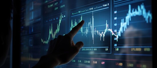 A hand pointing at the stock market chart on an interactive screen, with candlestick charts and trading data in dark blue tones. - obrazy, fototapety, plakaty