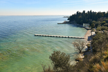 Elevated view of the Blondes Beach (Lido delle Bionde in Italian) with a wooden pier on Lake Garda, in winter, Sirmione, Brescia, Lombardy, Italy