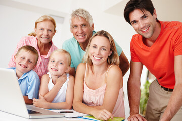 Obraz premium Happy, parents and grandparents in lounge on laptop with children for entertainment at home for development. Mom, dad and siblings bonding on vacation to visit grandma, grandpa and childhood house