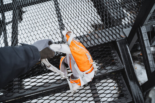 Person carrying a backpack near a chainlink wire fencing on stairs