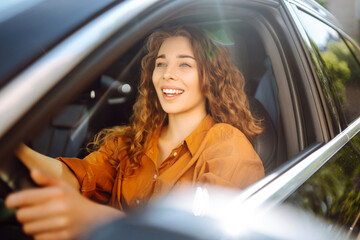 Portrait of young woman is driving a car and smiling. Automobile travel. Sharing a car. Lifestyle...