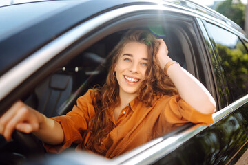 Portrait of young woman is driving a car and smiling. Automobile travel. Sharing a car. Lifestyle concept.