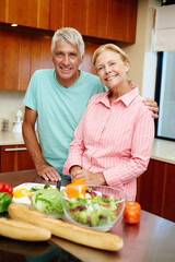 Senior man, woman and happy in cheerful, smile and cooking in kitchen at home for dinner, plans and family. Mature couple in preparing, food or salad for healthy, eating and nutrition in house