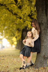 Family day. Young mom and little daughter having fun and enjoy relaxing outdoors in autumn park. Adorable child girl tightly hugs and kiss her mother. Maternal care and love for kid. Mothers day