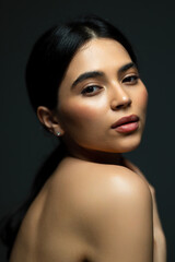 Beautiful face of young adult woman with clean fresh skin - isolated on dark background