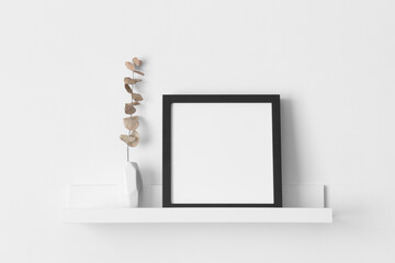 Black square frame mockup with an eucalyptus decoration on the wall shelf.