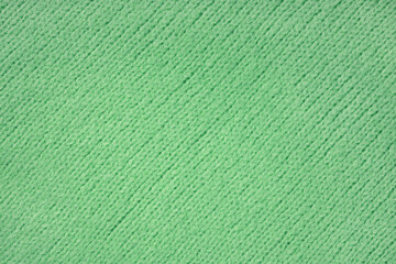 Obraz premium Green knitted woolen jersey fabric with diagonal weaving, sweater, pullover texture background. Fabric abstract backdrop, cloth wallpaper