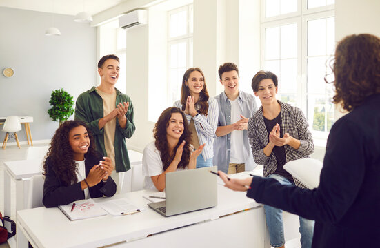 High school diverse happy smiling students at the lesson in modern classroom with laptop listening a male teacher standing back during a lesson and applauding him. Education and knowledge concept. - Powered by Adobe