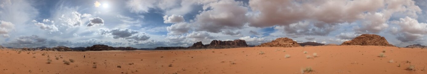 Panoramic view of Wadi Rum desert in Jordan with clouds moving over flat sand landscape with mountains and rocks formations.Discover beauty of the earth. National park outdoors landscape.UNESCO