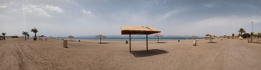 An empty sandy beach in Aqaba, Jordan, remains deserted following the Israeli-Palestine war. The peaceful scene contrasts with the recent history, highlighting the impact of conflict on tourism.


