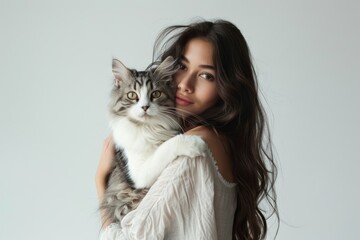 Pretty woman with her Maine coon cat in her arms putting their faces together