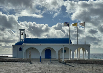 Die Ayia Thekla Kapelle mit wehenden Fahnen am Meer bei Ayia Napa, Zypern