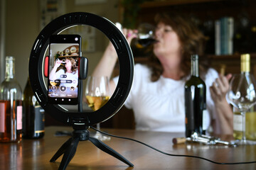 Female leading virtual wine tasting online video social media or live stream with light ring & phone