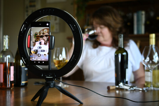 Female leading virtual wine tasting online video social media or live stream with light ring & phone