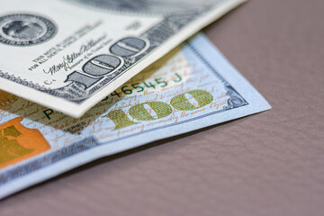 Close-up of US Dollar Bills on Surface. A detailed close-up capture of American currency, highlighting the intricate designs of the hundred-dollar bills. Selective focus