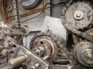 Sprockets and drive chain in an old industrial machine. Keeping machines in full working condition - obrazy, fototapety, plakaty