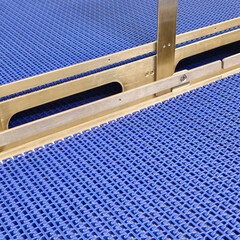 A close-up of a blue polyurethane belt in modular industrial conveyor system. Stainless steel...